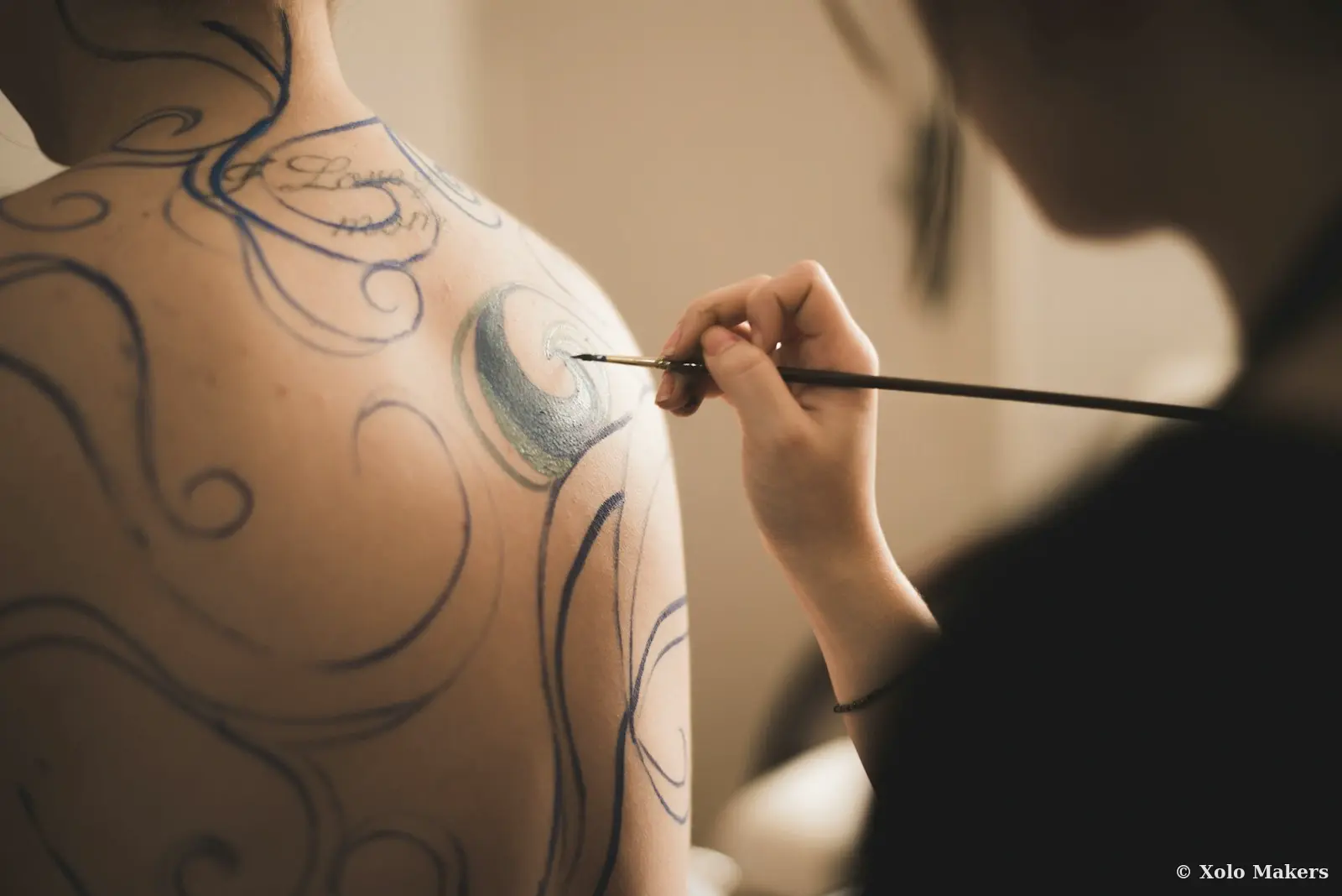 Artista aplicando bodypaint — servicio profesional Xolo Makers