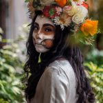 a person with a mask and flowers on their head